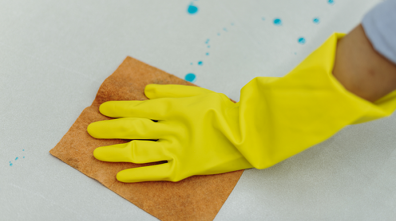 woman-wearing-yellow-rubber-gloves-cleaning-surface.png